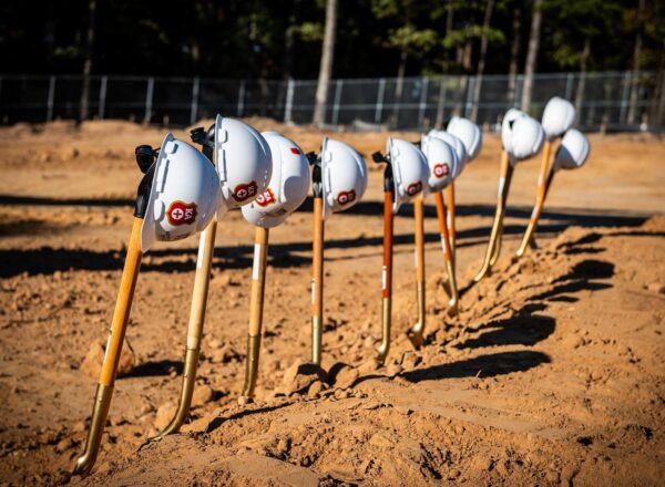 construction hard hats on shovels in a row on dirt