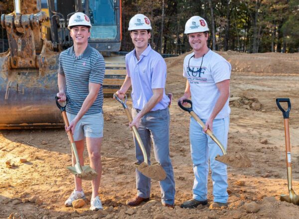 three men holding shovels and dirt