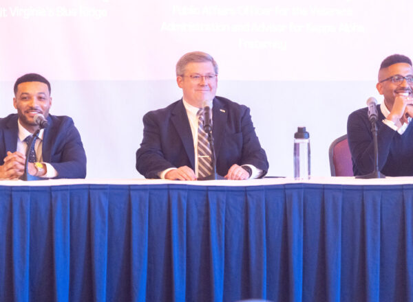 panel of three men on stage behind table