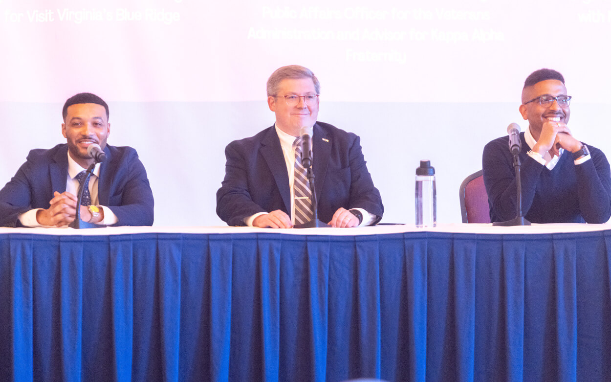 panel of three men on stage behind table