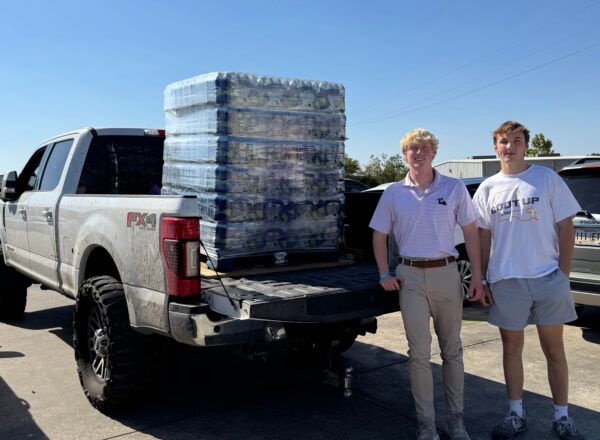 two brothers standing next to truck with pallet of water