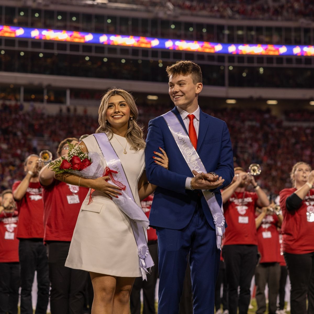 man and woman dressed with sashes for homecoming court