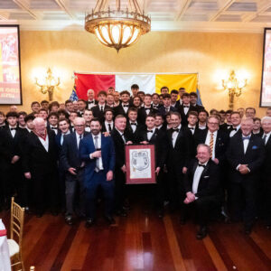 group photo of old and younger men in tuxes with framed charter