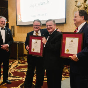 men in tuxedos holding framed certificates