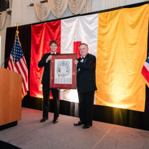 two men holding framed charter on stage