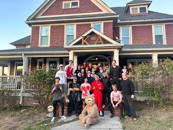 group of young men in halloween costumes on front porch of house