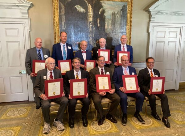 group of men sitting and standing with certificates