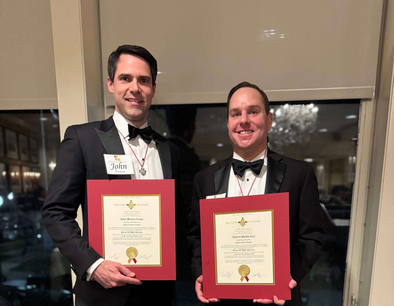 two men in tuxes holding certificates